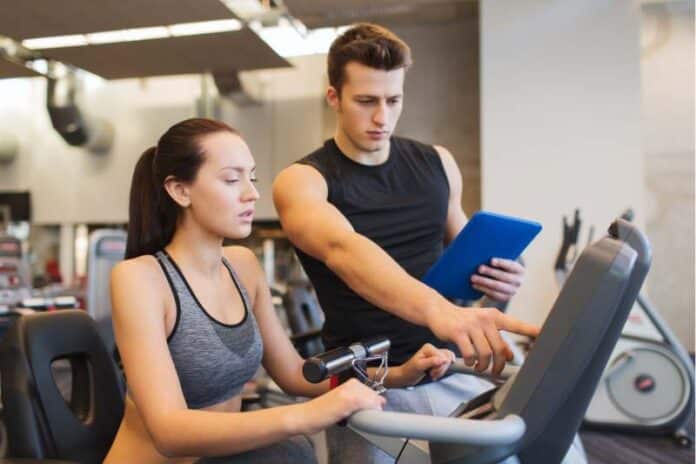 Woman with trainer working out exercise bike gym