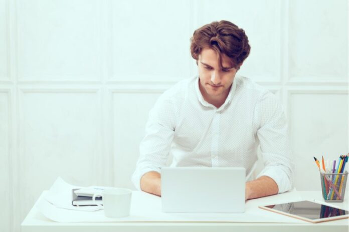 Businessman using laptop with tablet and pen