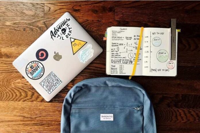 Flat lay photography of blue backpack beside book and silver macbook