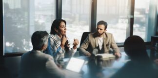 6 Signs It’s Time to Bring on a Manufacturer Representative Meeting, woman and collaboration with colleagues, boardroom and discussion for stats, team and company. Corporate, employees and people with info for business, planning and communication for updates.